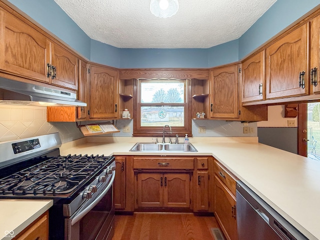 kitchen with appliances with stainless steel finishes, dark hardwood / wood-style floors, sink, decorative backsplash, and a textured ceiling