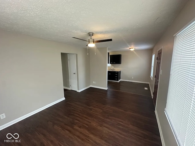 unfurnished living room with dark hardwood / wood-style floors, a textured ceiling, and ceiling fan