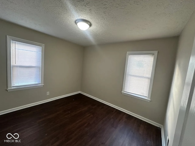 spare room with dark hardwood / wood-style floors, a textured ceiling, and a wealth of natural light