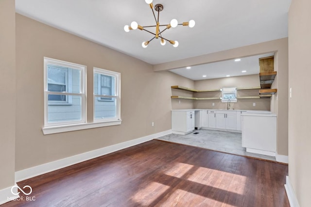 unfurnished living room featuring dark hardwood / wood-style floors, a chandelier, and sink