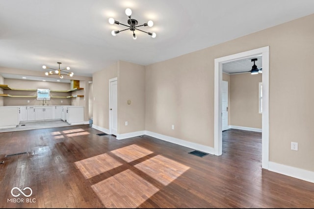 unfurnished living room featuring an inviting chandelier, sink, and dark hardwood / wood-style flooring