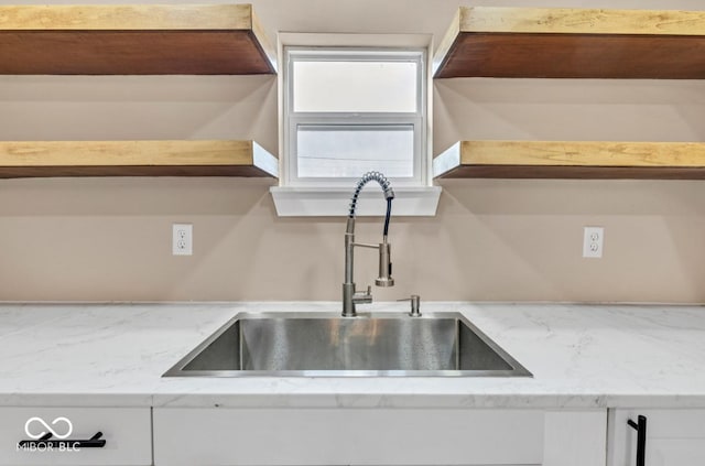 kitchen with white cabinetry, sink, and light stone counters