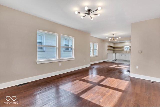 unfurnished living room with dark hardwood / wood-style flooring and a chandelier