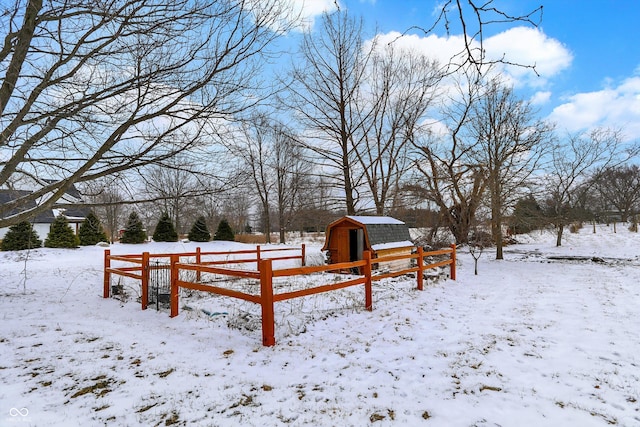 yard covered in snow with fence, a storage shed, and a garage