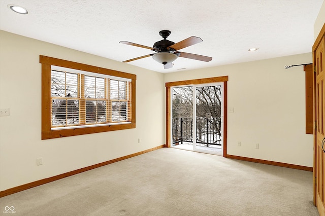 spare room featuring baseboards, light colored carpet, a ceiling fan, and a textured ceiling