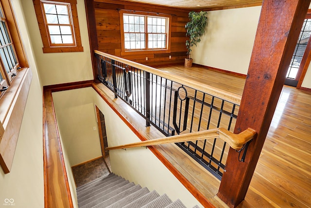 stairs with baseboards, wood finished floors, and wooden walls