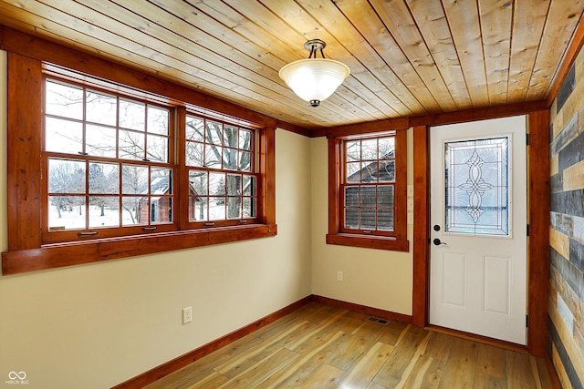 foyer entrance with light wood-style flooring, baseboards, wooden ceiling, and visible vents