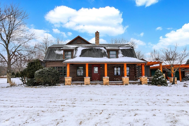 snow covered back of property featuring a chimney