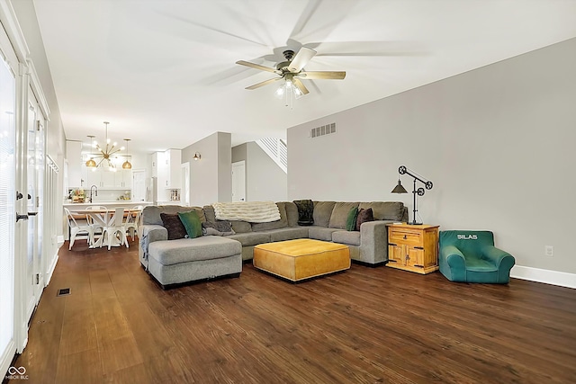 living room with dark wood-type flooring and ceiling fan with notable chandelier