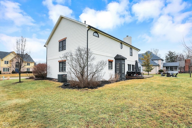 rear view of property featuring cooling unit and a lawn