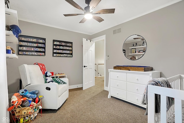 bedroom with a crib, crown molding, carpet flooring, and ceiling fan