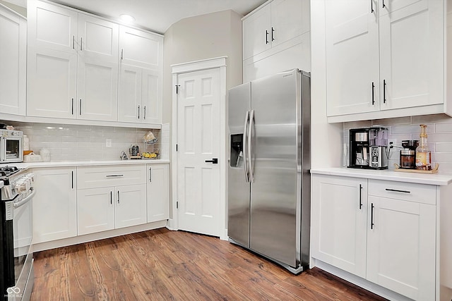 kitchen with white cabinetry, stainless steel appliances, tasteful backsplash, and hardwood / wood-style flooring