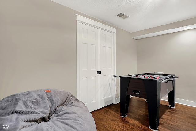 playroom with dark hardwood / wood-style floors and a textured ceiling