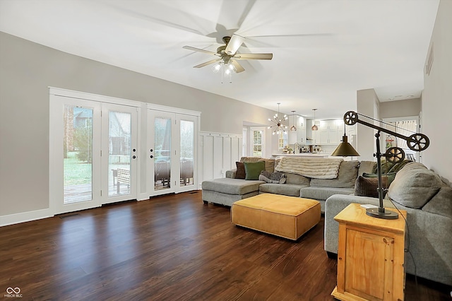 living room featuring ceiling fan with notable chandelier and dark hardwood / wood-style floors