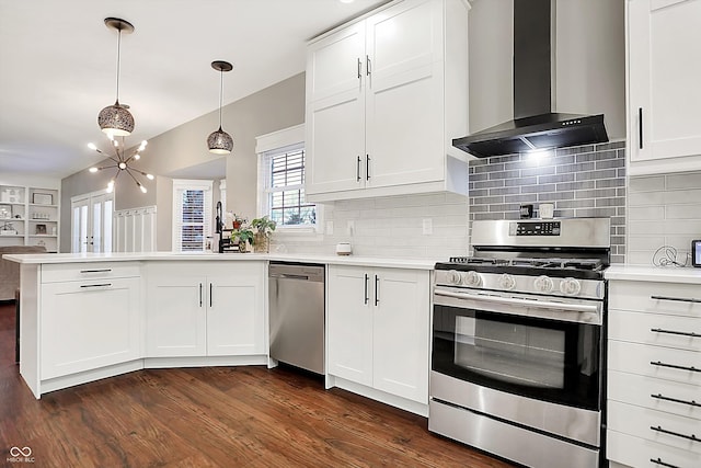 kitchen with pendant lighting, white cabinetry, stainless steel appliances, kitchen peninsula, and wall chimney exhaust hood