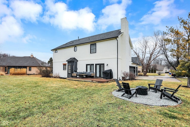 rear view of property featuring a garage, a lawn, and a fire pit