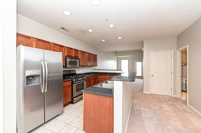 kitchen featuring sink, stainless steel appliances, a textured ceiling, light carpet, and kitchen peninsula