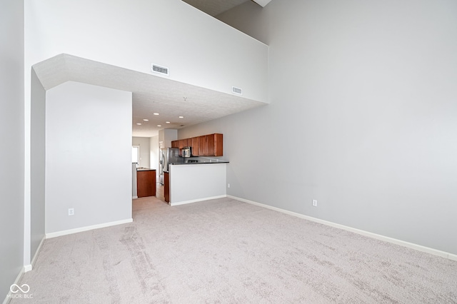 unfurnished living room with a high ceiling and light colored carpet