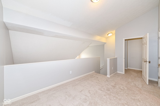 additional living space featuring lofted ceiling and light colored carpet