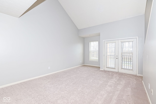 carpeted spare room with high vaulted ceiling and french doors