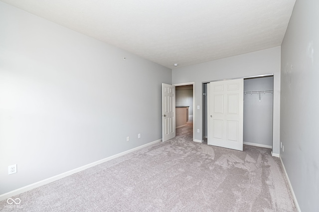 unfurnished bedroom with light colored carpet and a closet