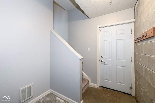 doorway with concrete flooring and a textured ceiling