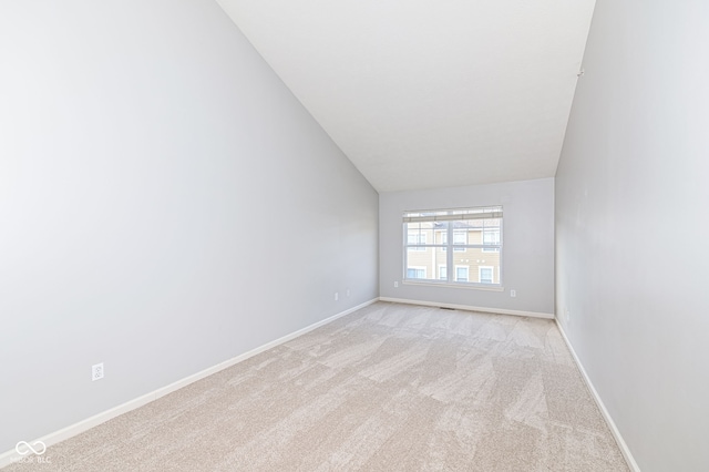 carpeted spare room with vaulted ceiling