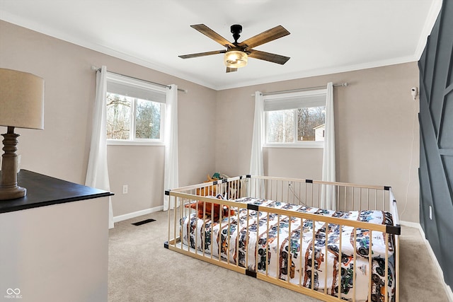 carpeted bedroom featuring multiple windows, ornamental molding, and ceiling fan