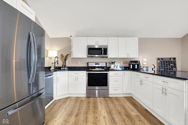 kitchen with white cabinetry, light hardwood / wood-style floors, stainless steel appliances, and kitchen peninsula