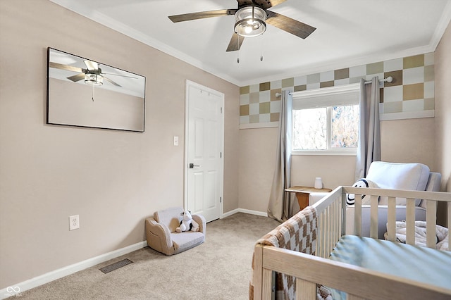 carpeted bedroom featuring a crib, ornamental molding, and ceiling fan