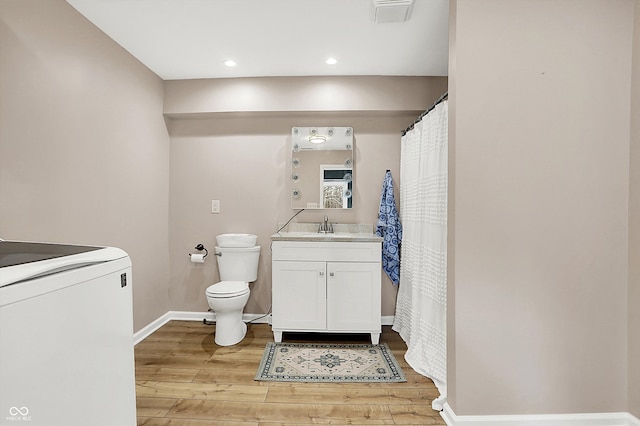 bathroom featuring toilet, vanity, washer / clothes dryer, and wood-type flooring