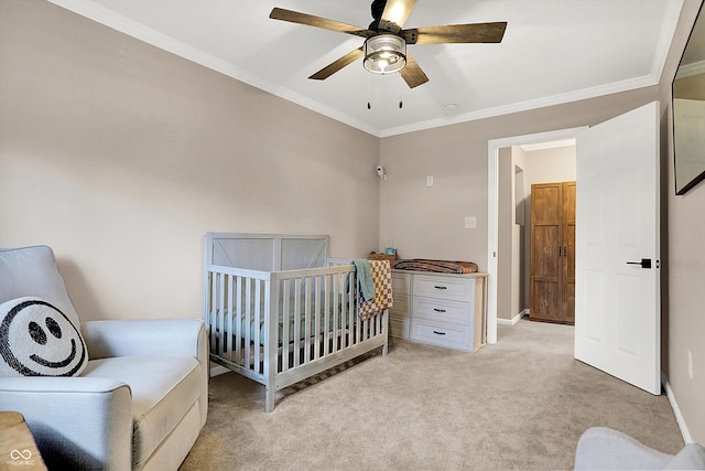 carpeted bedroom with a crib, ornamental molding, and ceiling fan