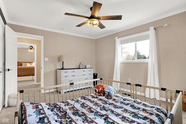 carpeted bedroom with ceiling fan, ornamental molding, and a crib