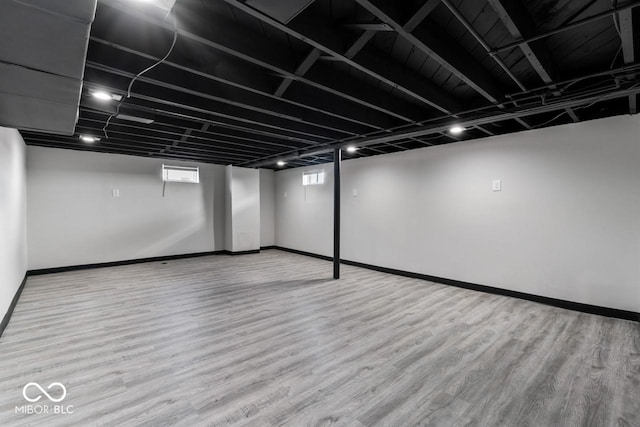 basement with plenty of natural light and light hardwood / wood-style flooring