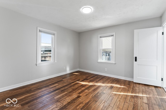 spare room with a healthy amount of sunlight and dark hardwood / wood-style flooring