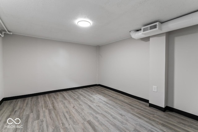 spare room featuring a textured ceiling and light wood-type flooring