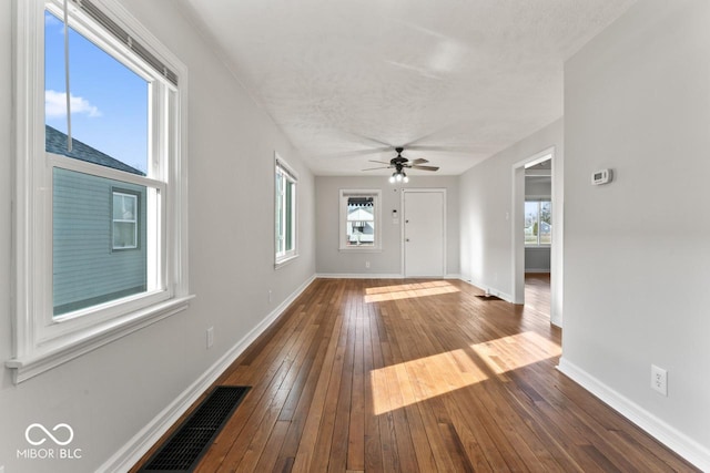 entryway with ceiling fan, a wealth of natural light, dark wood-type flooring, and a textured ceiling