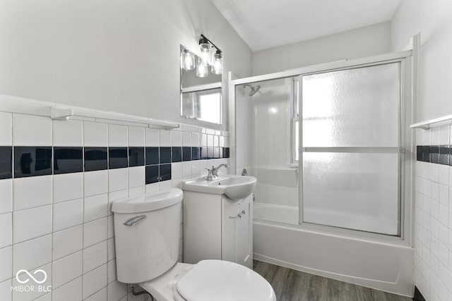 full bathroom featuring enclosed tub / shower combo, tile walls, hardwood / wood-style floors, vanity, and toilet