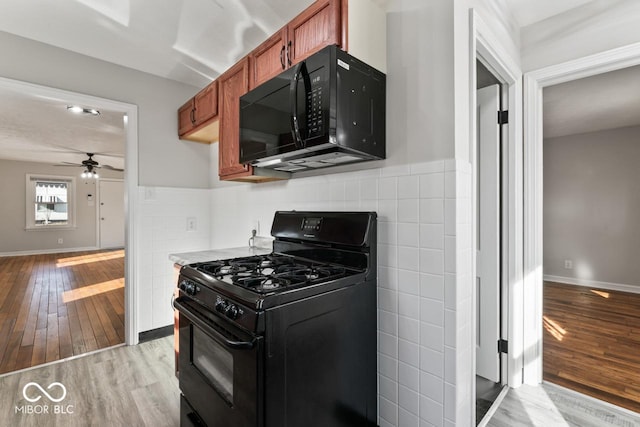 kitchen with tile walls, light hardwood / wood-style flooring, black appliances, and ceiling fan