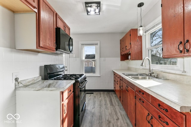 kitchen with sink, tile walls, pendant lighting, light hardwood / wood-style floors, and black appliances