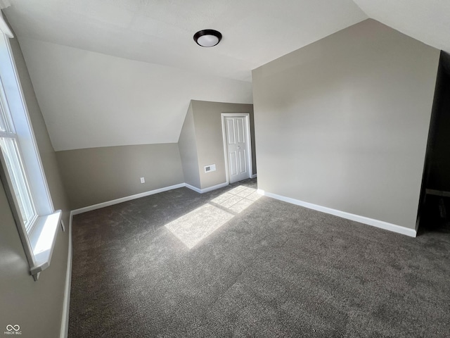 additional living space featuring lofted ceiling and dark carpet