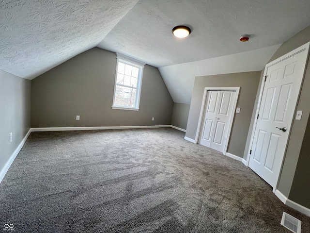 bonus room with lofted ceiling, carpet floors, and a textured ceiling