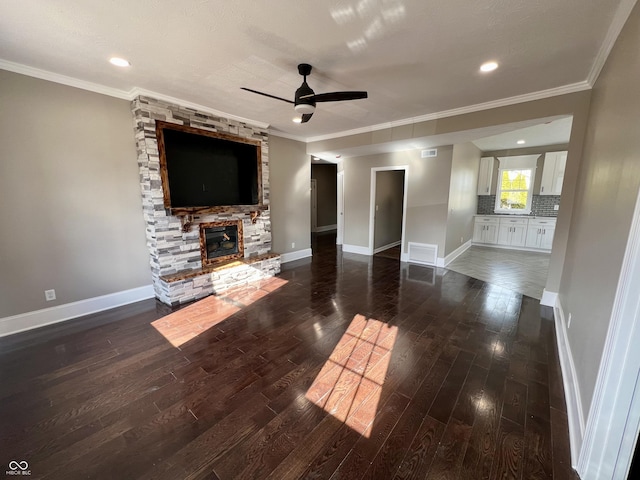 unfurnished living room with ornamental molding, dark hardwood / wood-style floors, ceiling fan, and a fireplace