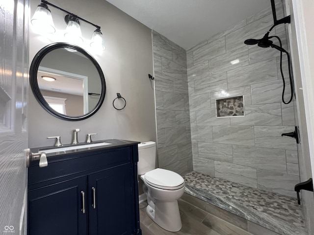 bathroom featuring vanity, tiled shower, and toilet