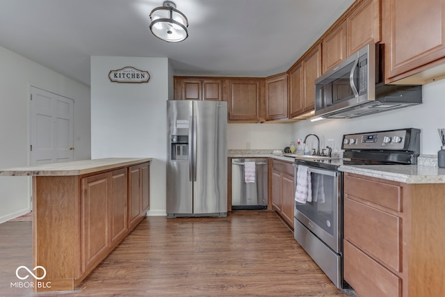 kitchen with a kitchen island, sink, wood-type flooring, and appliances with stainless steel finishes