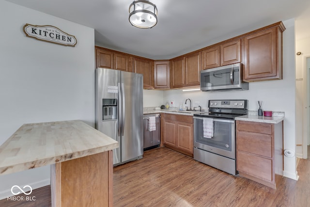 kitchen with appliances with stainless steel finishes, sink, and light wood-type flooring