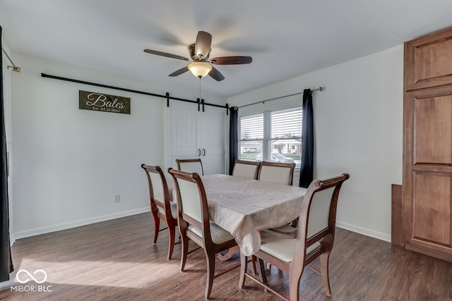 dining space with a barn door, dark hardwood / wood-style floors, and ceiling fan