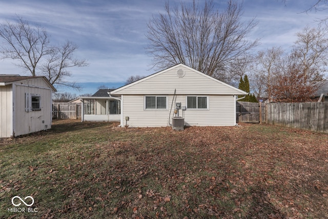 back of property with a lawn, central AC unit, and a shed