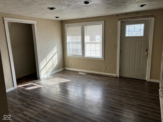 entrance foyer with dark wood-type flooring and a textured ceiling