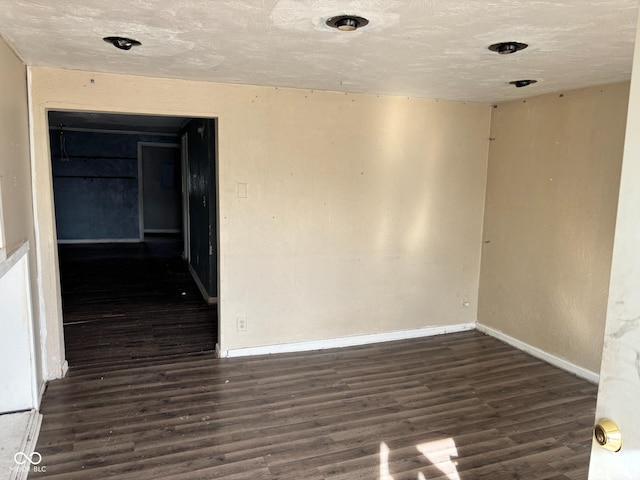 empty room featuring dark wood-type flooring and a textured ceiling